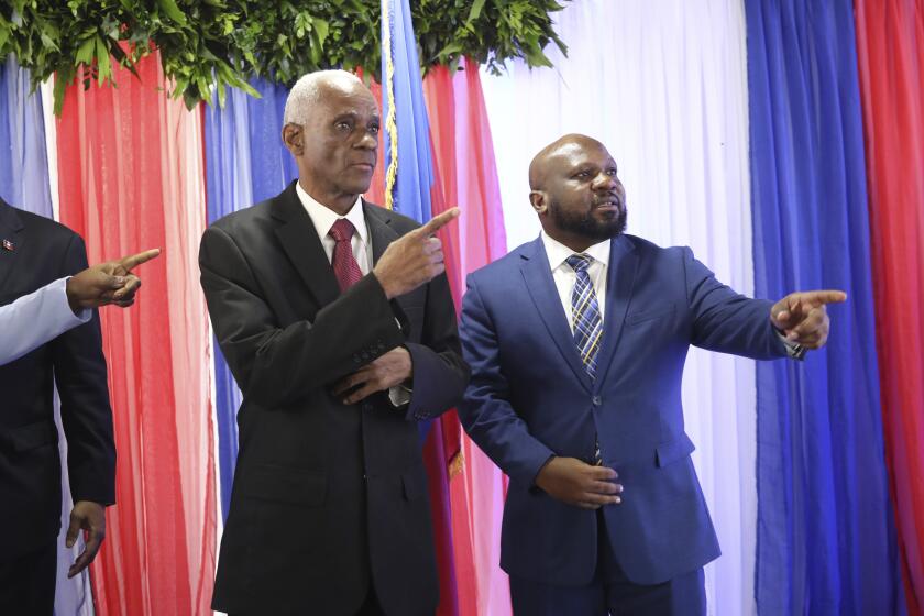 Edgard Leblanc Fils, a la izquierda, y Smith Augustin se preparan para una foto de grupo con el consejo de transición después de que Fils fuera nombrado presidente del organismo, en Puerto Príncipe, Haití, el martes 30 de abril de 2024. . (AP Foto/Odelyn Joseph)