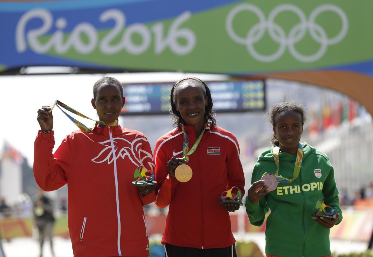 En imagen de archivo del domingo 14 de agosto de 2016, la medallista de plata Eunice Jepkirui Kirwa, izquierda, de Bahréin; la medallista de oro Jemima Jelagat Sumgong, centro, de Kenia; y la medallista de bronce Mare Dibaba, de Etiopía, posan desde el podio después del maratón de mujeres en los Juegos Olímpicos de Río de Janeiro, Brasil.