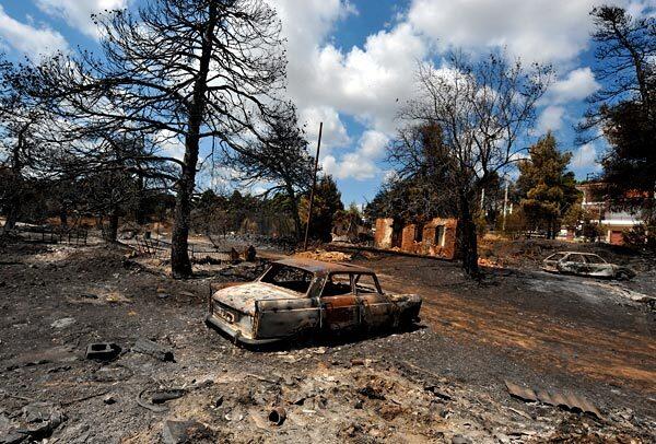 Burned-out cars sit amid a desolate landscape in an Athens suburb after wildfires devastated the outskirts of the Greek capital.