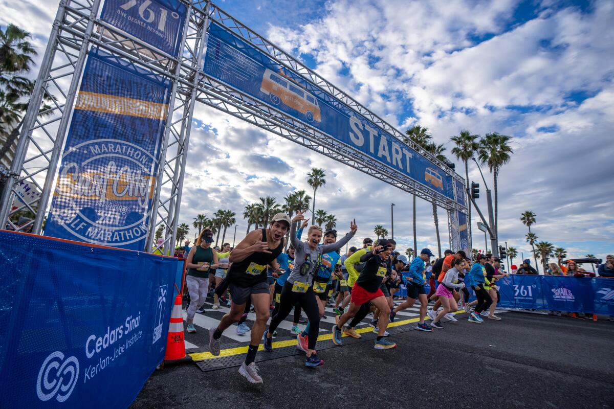 Runners celebrate while crossing the finish line at the Surf City Marathon on Sunday in Huntington Beach.