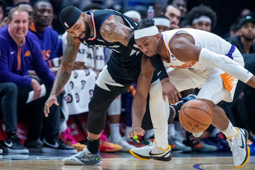 Clippers forward Marcus Morris Sr., #8, left, battles Suns guard Josh Okogie for a loose ball