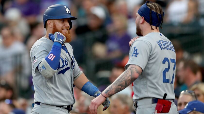 The Dodgers' Justin Turner, left, is congratulated by teammate Alex Verdugo after hitting a solo home run in the fifth inning against the Colorado Rockies in Denver on Thursday.