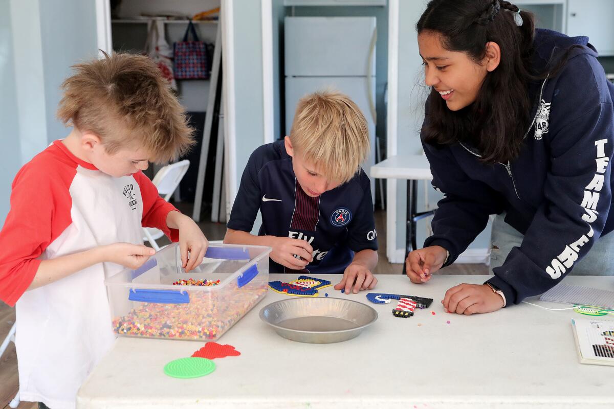 Junior counselor Alyssa Soto helps Elio Harness-Tognoli and Mason Hatch make bead designs at Halecrest Park.