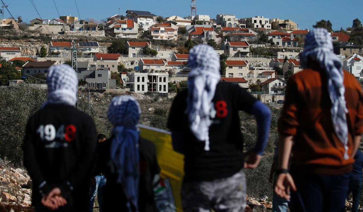 Palestinians stand facing the Israeli settlement of Qadumim in the village of Kfar Qaddum, near Nablus, in the occupied West Bank on Dec. 30, 2016.