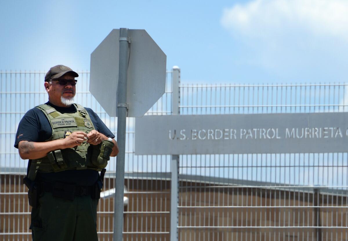 A U.S. Border Patrol agent keeps watch outside the entrance to the Border Patrol facility in Murrieta during a protest there Monday.