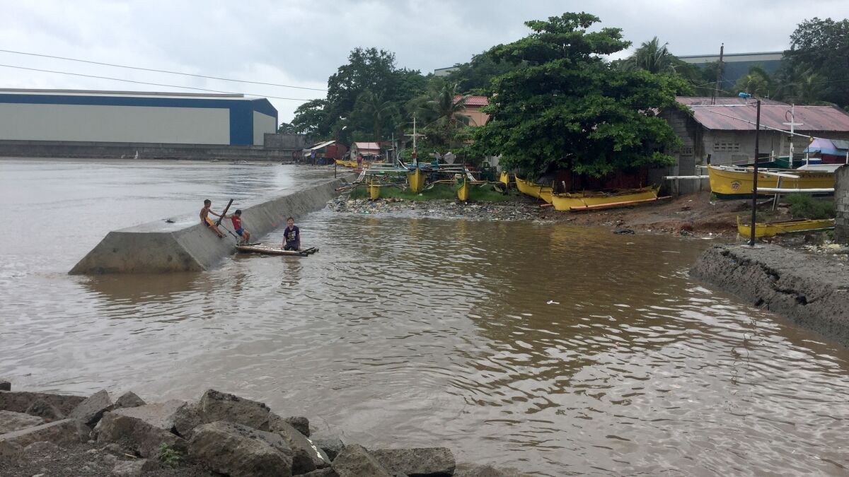 Children swim near the Seafront coal stockpile down the road from Capitan's home.