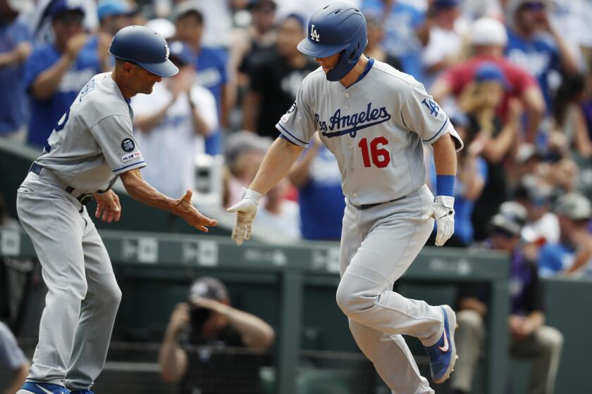 Los Angeles Dodgers third base coach Dino Ebel, left, congratulates Will Smith as he circles the bases after hitting a three-run home run off Colorado Rockies relief pitcher Wade Davis in the ninth inning of a baseball game Wednesday, July 31, 2019, in Denver. The Dodgers won 5-1. (AP Photo/David Zalubowski)