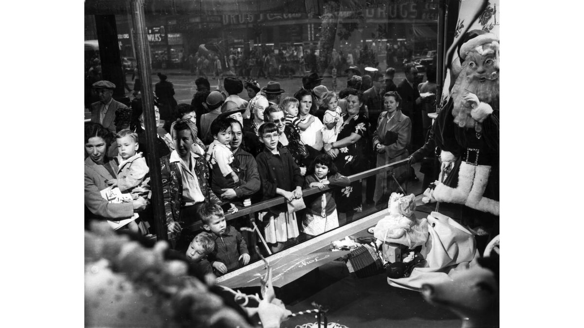 December 1950: Holiday shoppers watch animated Christmas display in downtown Los Angeles department store window. The window featured a moving Santa Claus, right.
