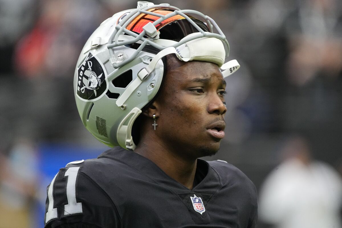 Raiders wide receiver Henry Ruggs III looks on during a game with his helmet pushed up on top of his head.