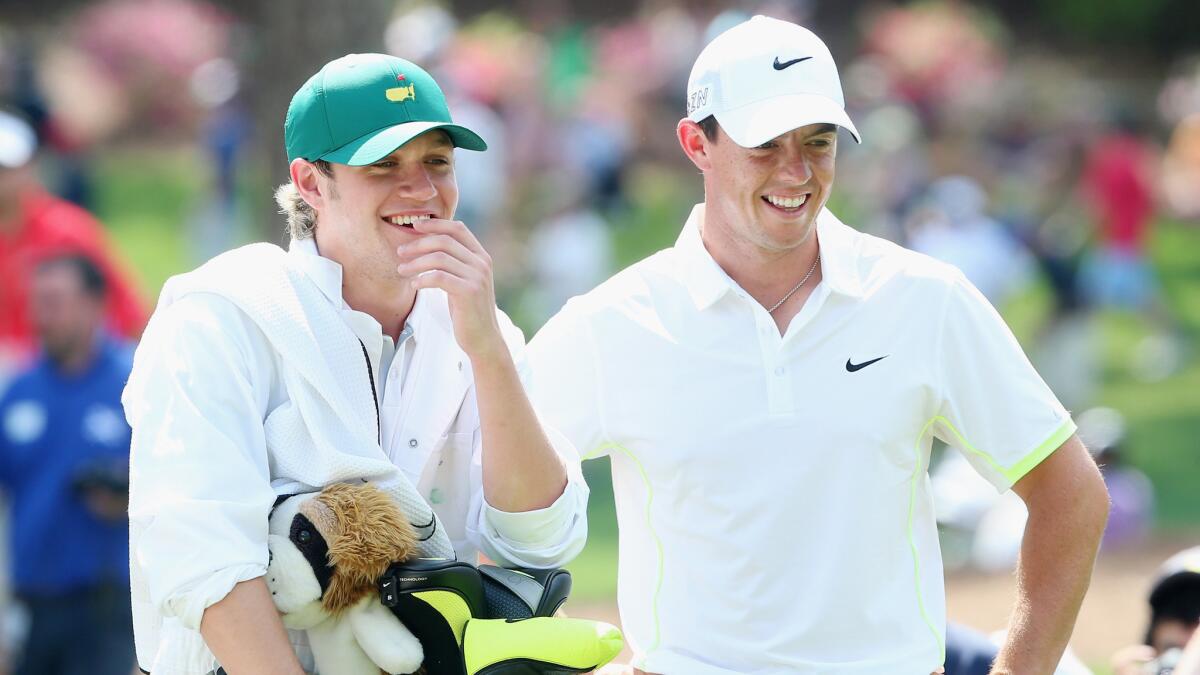 Caddie Niall Horan of One Direction and Rory McIlroy smile during the Par 3 Contest at Augusta National Golf Club on April 8.