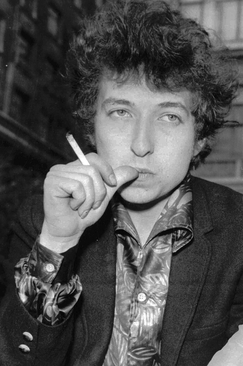 A black-and-white photo of a man in the 1960s holding a cigarette and biting his thumb.