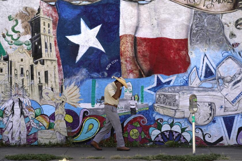 A man adjusts his face mask as he walks past a mural in the heavily Latino section of Oak Cliff in Dallas, Wednesday, Sept. 22, 2021. Texas this week will begin redrawing congressional lines, and Latino advocates and officeholders say it's time to correct past wrongs. The state's explosive population growth over the past decade, half of which comes from Latinos, has earned it two new congressional seats. At least one should be a Latino-majority congressional seat in the Dallas area, they argue. (AP Photo/LM Otero)