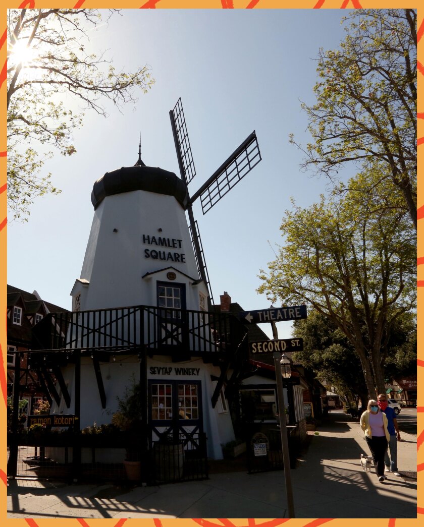 Pedestrians walk past a decorative windmill