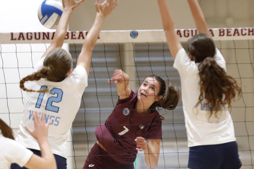 Kyra Zaengle (7) of Laguna Beach puts a kill past the block of Addison Brown during Wave League girls' volleyball game against Marina on Tuesday.