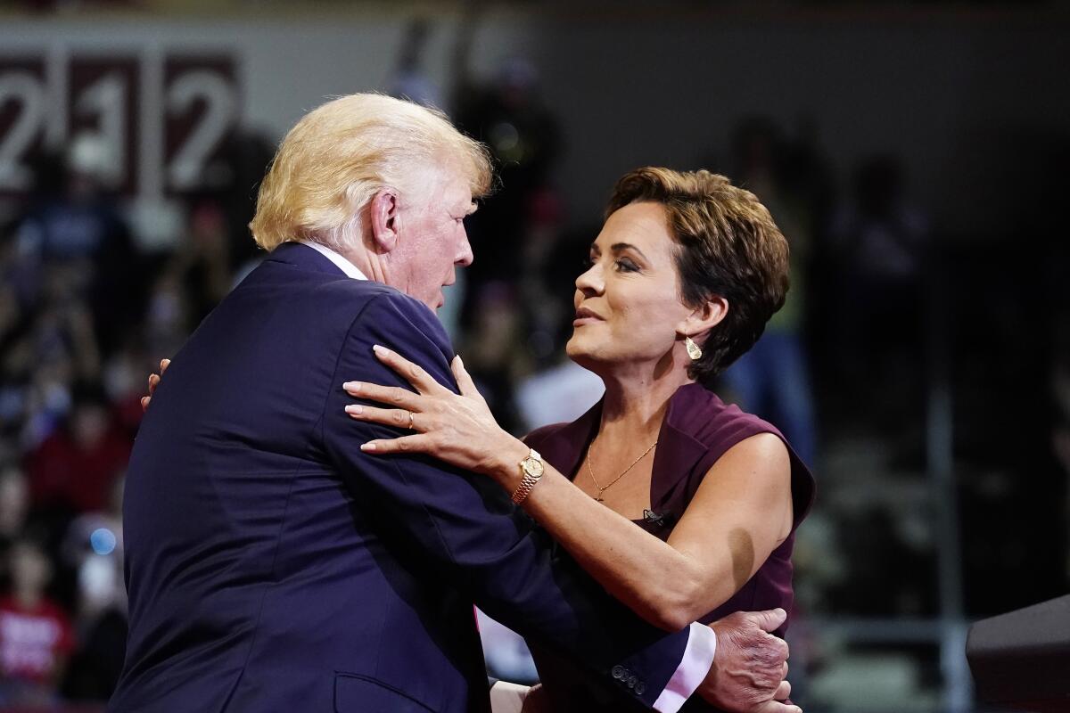 Donald Trump embraces Kari Lake on a stage