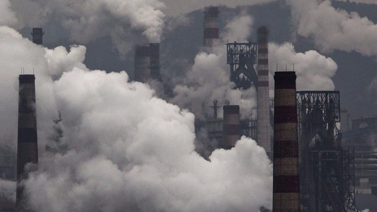 Smoke billows from smokestacks and a coal-fired generator at a steel factory in China. Scientists have developed a new method for tracking countries' compliance with the goals set forth in the Paris Agreement.