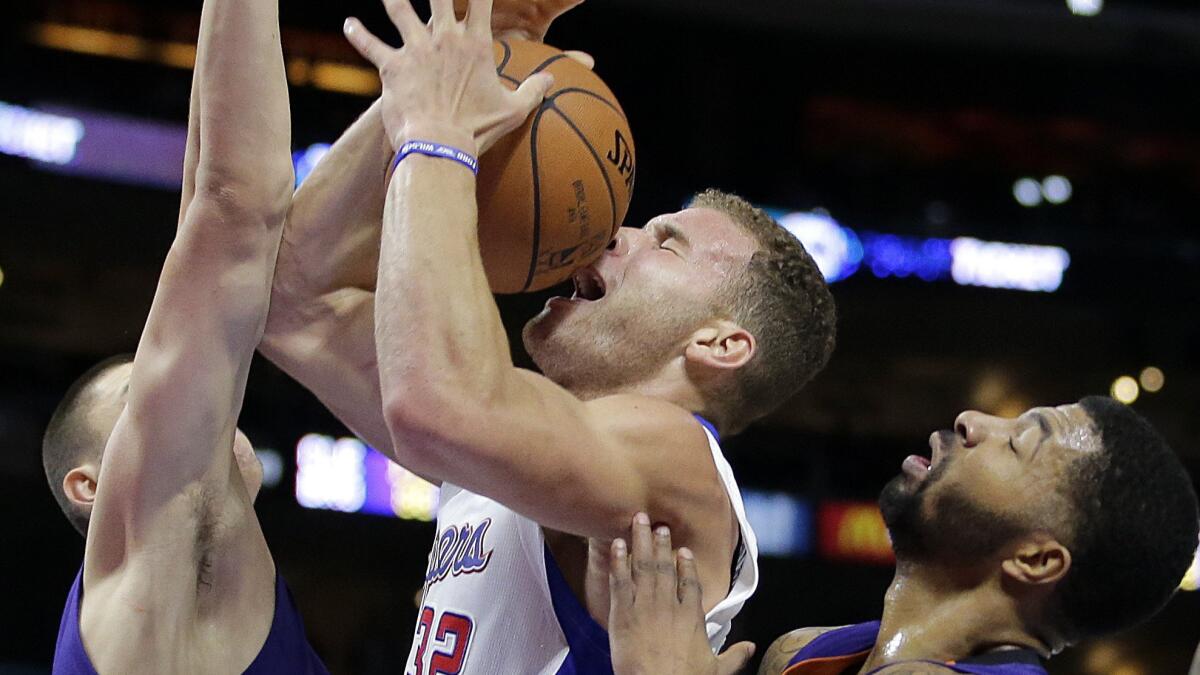 Clippers forward Blake Griffin, center, tries to put up a shot between Phoenix Suns center Alex Len, left, and forward Markieff Morris during the first half of Monday's game at Staples Center.