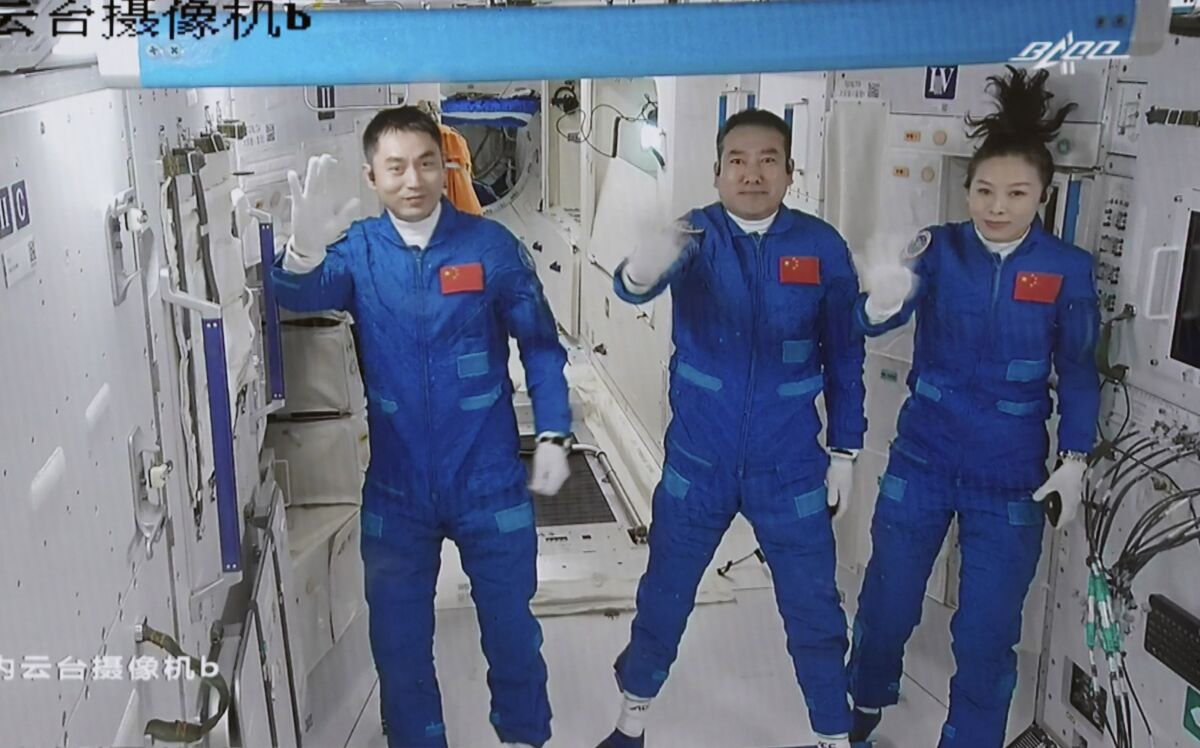 In this photo released by Xinhua News Agency, screen image captured at Beijing Aerospace Control Center in Beijing, China, Saturday, Oct. 16, 2021 shows three Chinese astronauts, from left, Ye Guangfu, Zhai Zhigang and Wang Yaping waving after entering the space station core module Tianhe. China's Shenzhou-13 spacecraft carrying three Chinese astronauts on Saturday docked at its space station, kicking off a record-setting six-month stay as the country moves toward completing the new orbiting outpost. Chinese characters, left, read "Platform Camera B." (Tian Dingyu/Xinhua via AP)