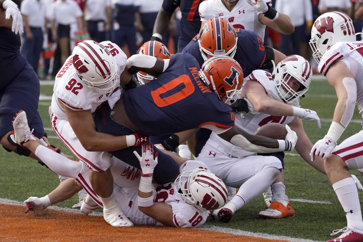 Illinois running back Joshua McCray sticks the ball over the goal line to avoid a safety as Wisconsin defensive end Matt Henningsen (92) and Collin Wilder (18) make the tackle during the first half of an NCAA college football game Saturday, Oct. 9, 2021, in Champaign, Ill. (AP Photo/Charles Rex Arbogast)