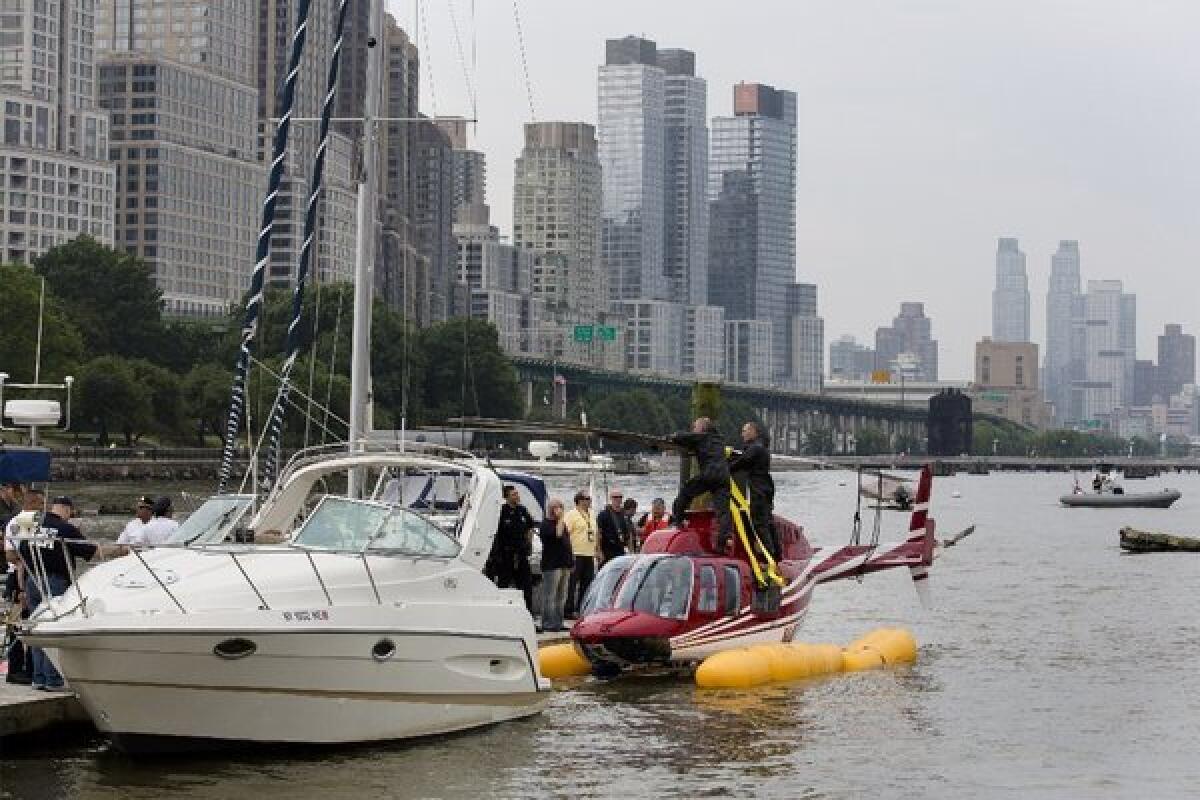 A helicopter rests on pontoons at the 79th Street Boat Basin in New York after an emergency landing on the Hudson River.