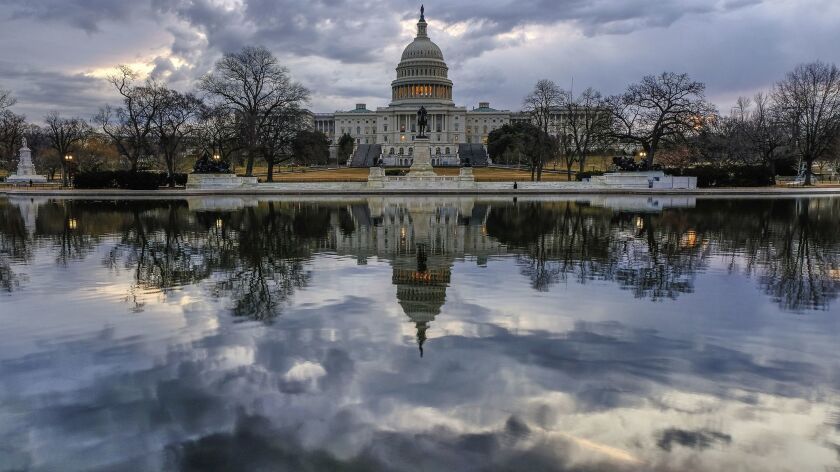 Clouds are reflected in the U.S. Capitol reflecting pool at daybreak.