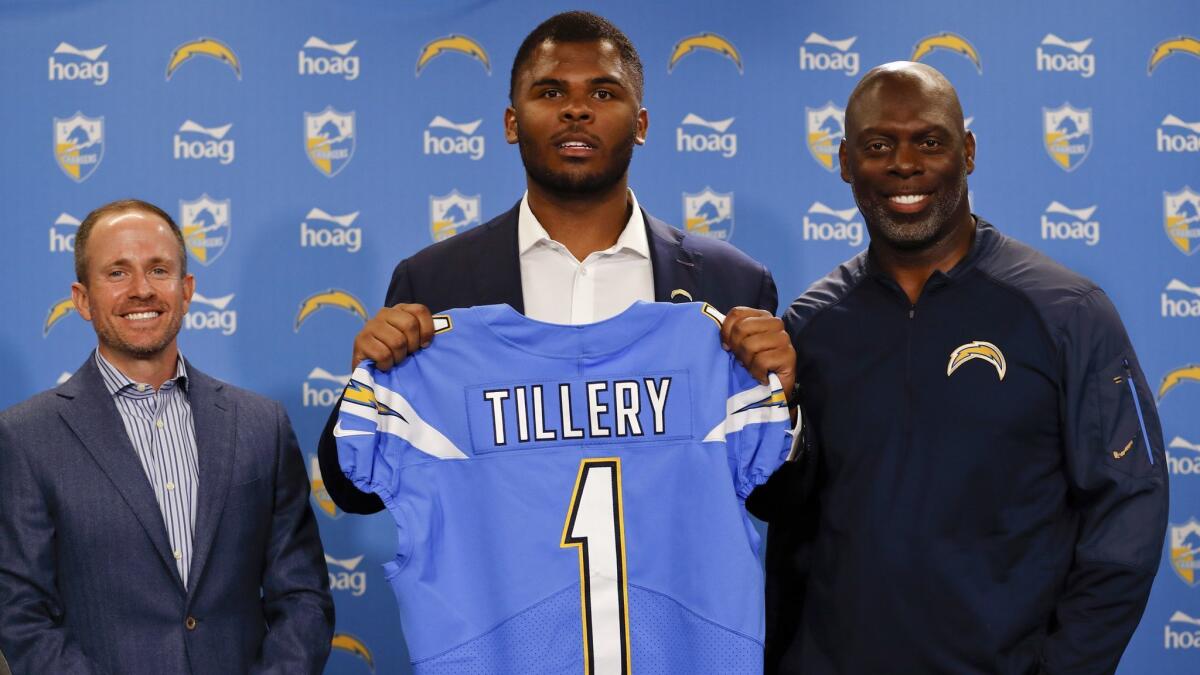 Chargers defensive tackle Jerry Tillery, center, poses with a jersey alongside coach Anthony Lynn, right, and president of football operations John Spanos, left, during a news conference at Chargers headquarters on Friday in Costa Mesa.