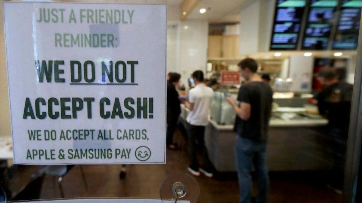 A sign posted on a door alerting customers that cash is not accepted at Freshroll Vietnamese Rolls & Bowls in San Francisco.