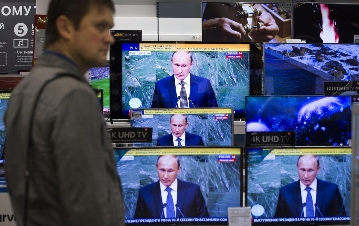 A man looks at television screens in a Moscow shop as Russian President Vladimir Putin addresses the United Nations on Sept. 28, 2015.