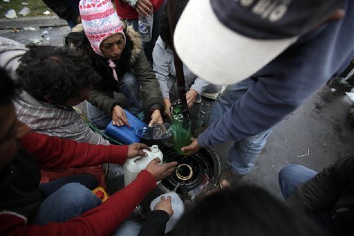 People draw fuel from an underground tank during looting in a gas-station in Concepcion, Chile, Sunday, Feb. 28, 2010. A 8.8-magnitude earthquake hit Chile early Saturday. (AP Photo/ Natacha Pisarenko)