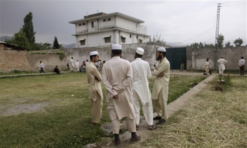 Pakistani men stand looking at the house where al-Qaida leader Osama bin Laden was caught and killed in Abbottabad, Pakistan, Thursday, May 5, 2011. The residents of Abbottabad were still confused and suspicious about the killing of bin Laden, which took place in their midst before dawn on Monday. (AP Photo/Muhammed Muheisen)