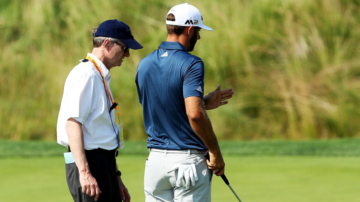 Dustin Johnson talks to a USGA rules official about his ball moving while on the fifth green Sunday during the final round of the U.S. Open