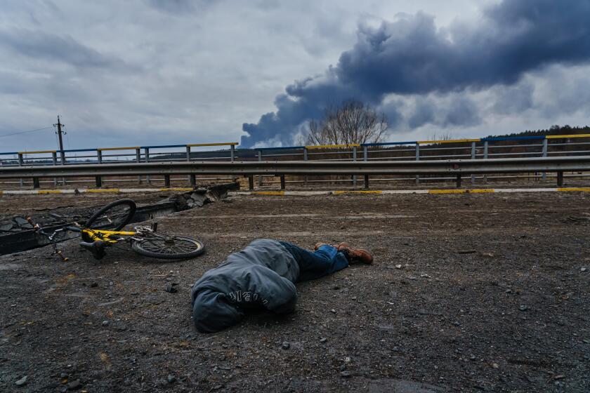 IRPIN, UKRAINE -- MARCH 7, 2022: A civilian body lays dead on the ground, on the destroyed bridge overlooking the Irpin river, as Russian forces continue to bombard and advance their forces, in Irpin, Ukraine, Monday, March 7, 2022. (MARCUS YAM / LOS ANGELES TIMES)
