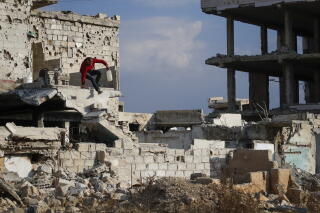 Samir al-Baghdadi, 46, jumps from a wall of his family home which was destroyed in the civil war
