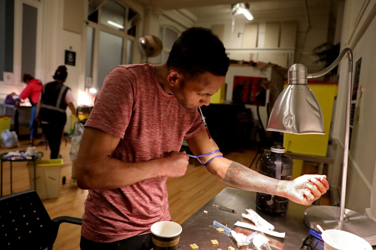 A person in Vancouver puts a tourniquet on his arm before taking an injection