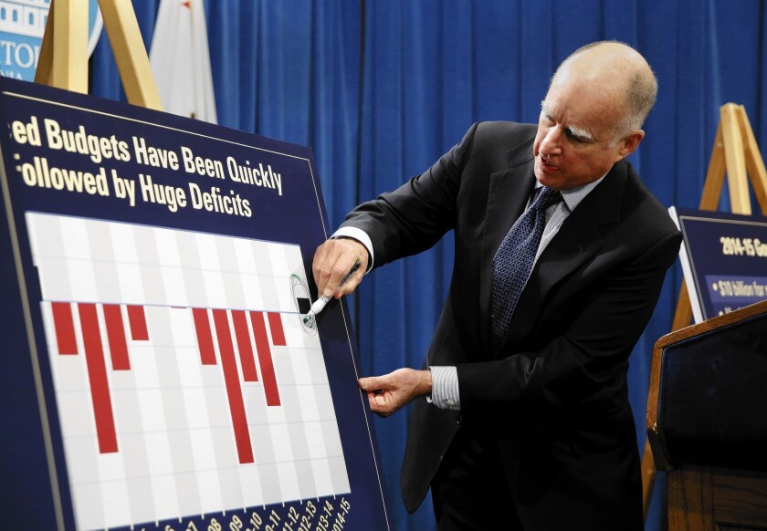 During a Sacramento news conference at which he unveiled his proposed 2014-15 state budget, Gov. Jerry Brown circles the black bar showing a surplus projected for the coming year, after years of deficits, represented in red.