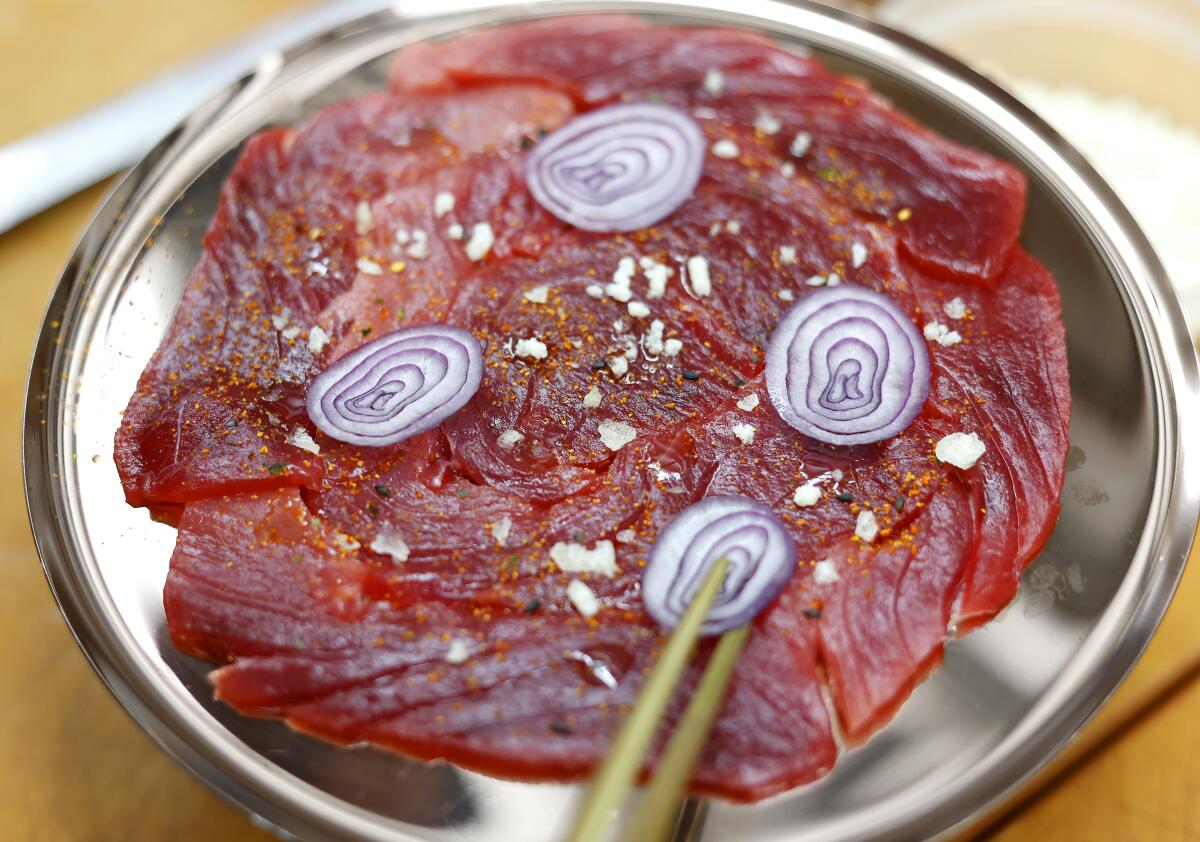 Thinly sliced shallot is added atop local bluefin tuna carpaccio.