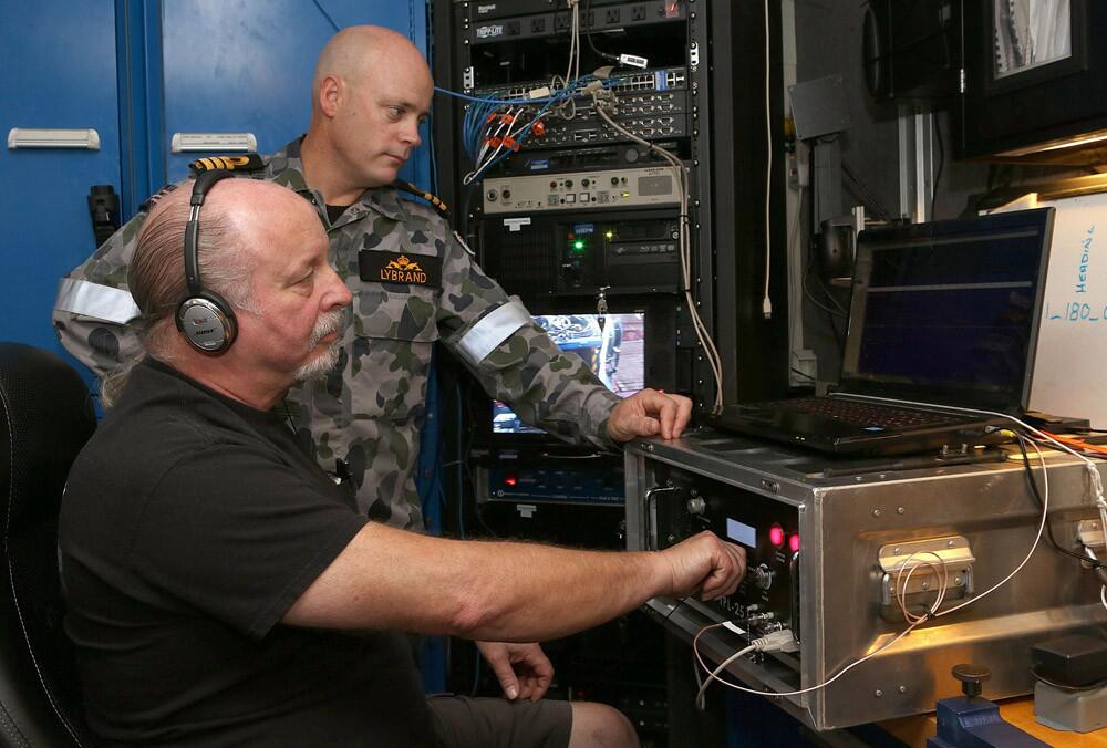 A handout photo taken on April 5, 2014 and released on April 7 by the Australian Defense shows Commander James Lybrand, Mission Commander on the Australian Defense Vessel Ocean Shield, watching as Mike Unzicker from Phoenix International monitors the feed from the towed pinger locator during the search for missing Malaysia Airlines Flight MH370 in the southern Indian Ocean.