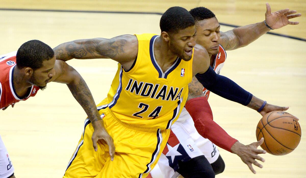 Pacers forward Paul George (24) tries to maintain control of the ball as he's defended by Wizards forward Trevor Ariza, left, and guard Bradley Beal on Friday night.