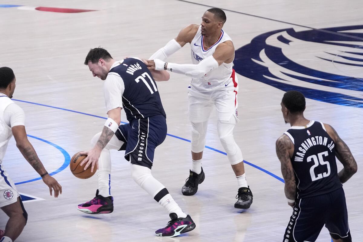 Dallas Mavericks' Luka Doncic (77) is fouled by Los Angeles Clippers' Russell Westbrook.