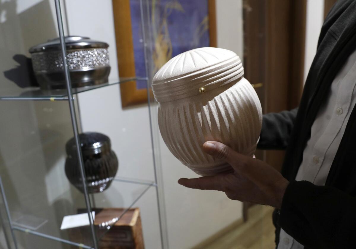 A man holds an urn at a funeral parlor in Rome, Tuesday, Oct. 25, 2016.