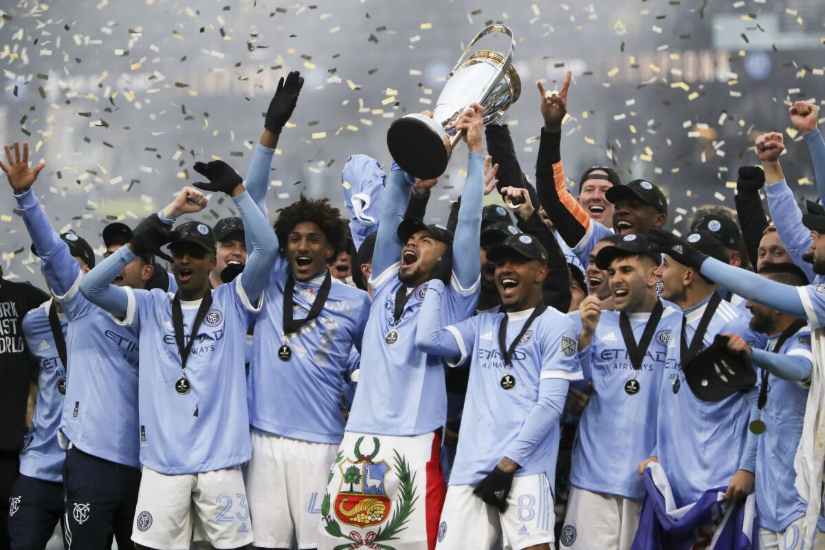 New York City FC players celebrate with the trophy after their penalty kick shootout win over the Portland Timbers in the MLS Cup soccer game, Saturday, Dec. 11, 2021, in Portland, Ore. (AP Photo/Amanda Loman)