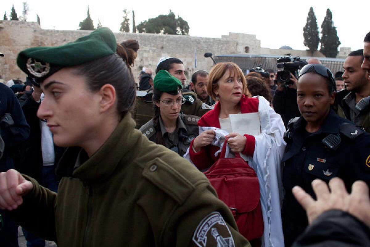 Israeli policewomen detain a member of the religious group Women of the Wall who was wearing a Jewish prayer shawl at the Western Wall.