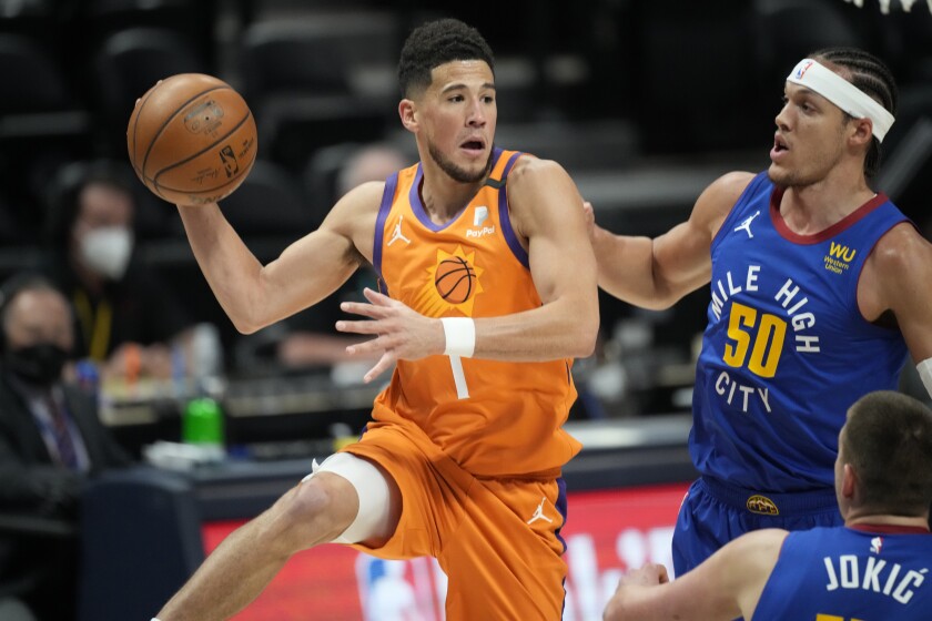 Phoenix Suns guard Devin Booker, left, passes the ball as Denver Nuggets forward Aaron Gordon defends during the first half of Game 3 of an NBA second-round playoff series Friday, June 11, 2021, in Denver. (AP Photo/David Zalubowski)