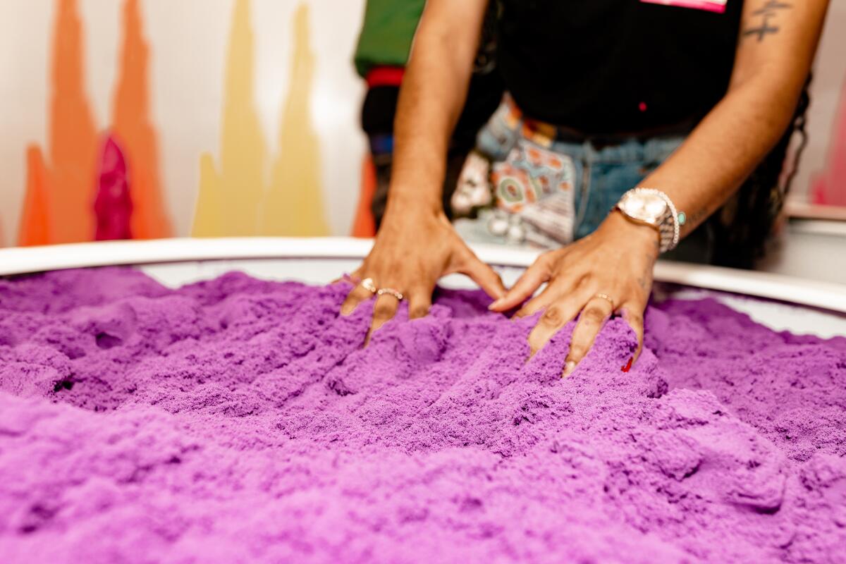 A person with their hands in a vat of purple slime