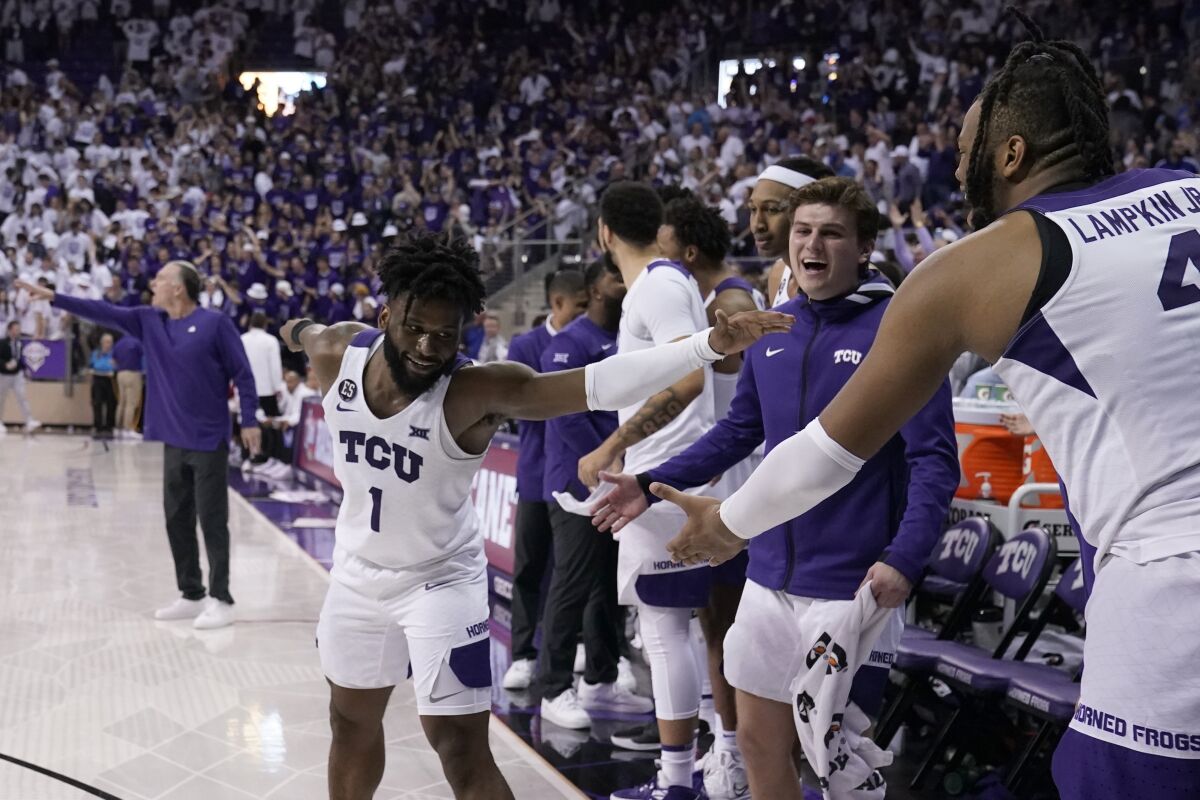 TCU guard Mike Miles (1), Eddie Lampkin (4) and the rest of the bench celebrate in the final seconds of the second half of an NCAA college basketball game against Kansas in Fort Worth, Texas, Tuesday, March 1, 2022. (AP Photo/Tony Gutierrez)