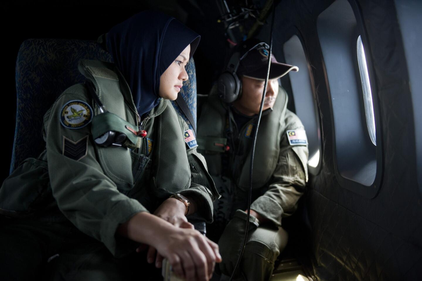 Crew members look outside windows from a Malaysian Air Force CN235 aircraft during a search and rescue operation to find the missing Malaysia Airlines flight MH370 plane over the Strait of Malacca on March 15.