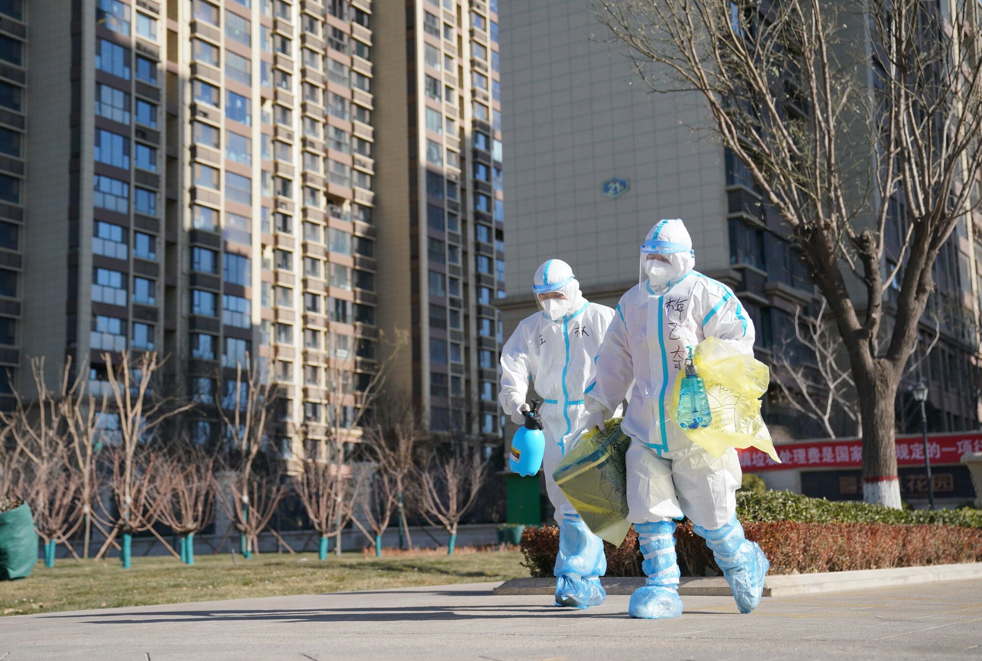 Workers carry a container of coronavirus test samples outside a neighborhood in Shijiazhuang, China.