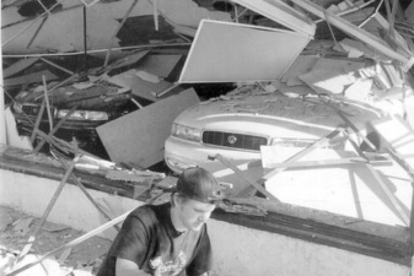 David Lane checks damage in front of a Mazda dealership in Santa Monica after the 1994 Northridge earthquake. Santa Monica adopted regulations on retrofitting vulnerable buildings, but its resolve has faded in recent years.