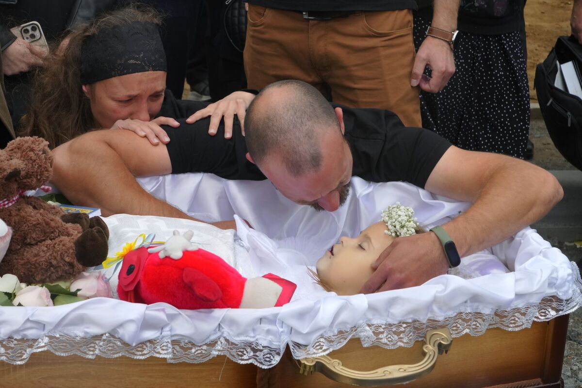 Artem Dmitriev gives the last salute to his daughter Liza, 4-year-old girl killed by Russian attack, in Vinnytsia, Ukraine, Sunday, July 17, 2022. Wearing a blue denim jacket with flowers, Liza was among 23 people killed, including two boys aged 7 and 8, in Thursday's missile strike in Vinnytsia. Her mother, Iryna Dmytrieva, was among the scores injured. (AP Photo/Efrem Lukatsky)