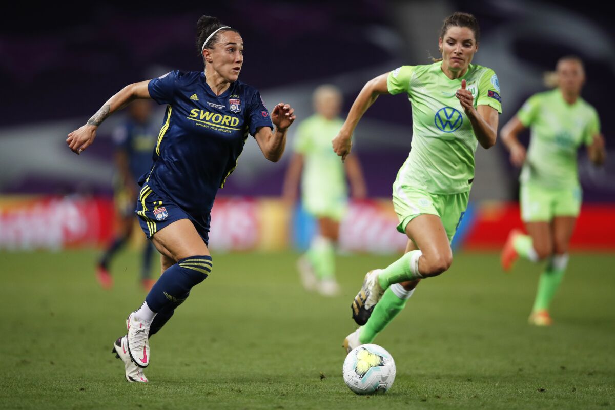 Lyon's Lucy Bronze, left, runs with the ball followed by Wolfsburg's Dominique Janssen during the Women's Champions League final soccer match between Wolfsburg and Lyon at the Anoeta stadium in San Sebastian, Spain, Sunday, Aug. 30, 2020. (Clive Brunskill/Pool via AP)